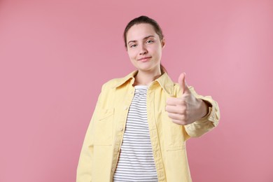 Photo of Woman showing thumbs up on pink background. Like gesture