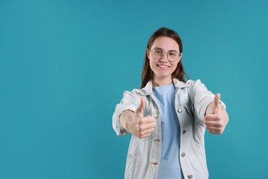 Photo of Happy woman showing thumbs up on light blue background, space for text. Like gesture