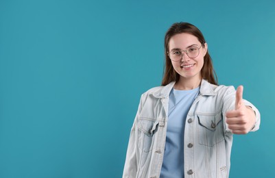 Photo of Happy woman showing thumbs up on light blue background, space for text. Like gesture