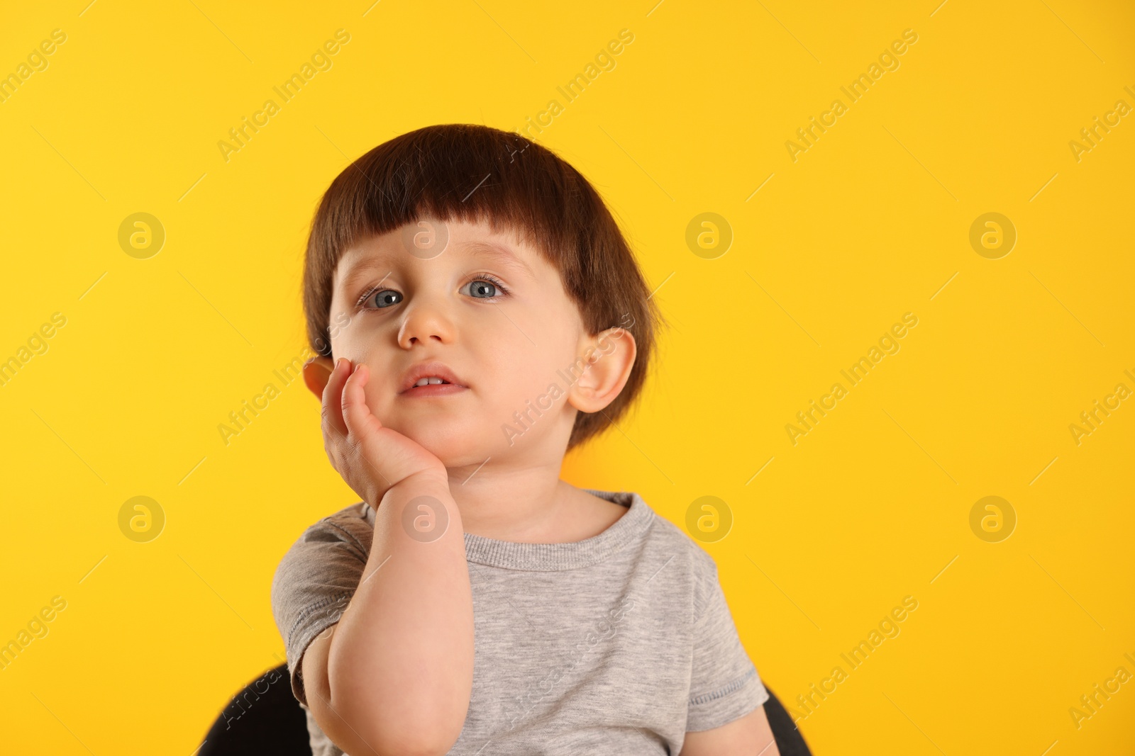 Photo of Portrait of cute little boy on yellow background. Space for text