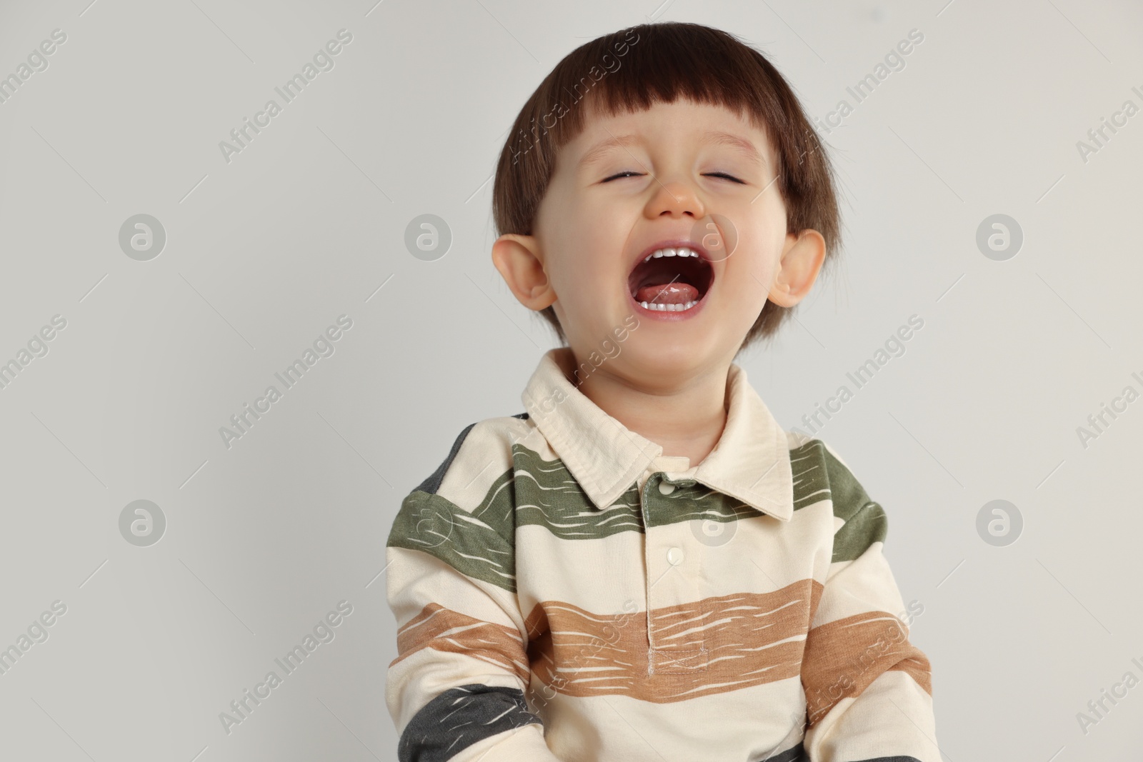 Photo of Portrait of emotional little boy on light grey background. Space for text