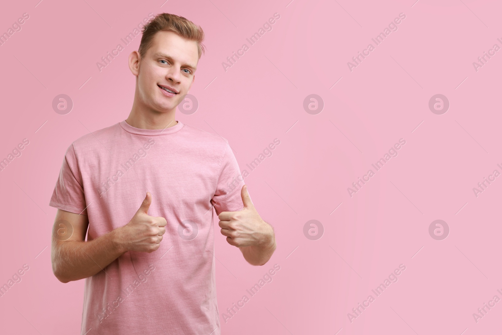 Photo of Happy man showing thumbs up on pink background, space for text. Like gesture