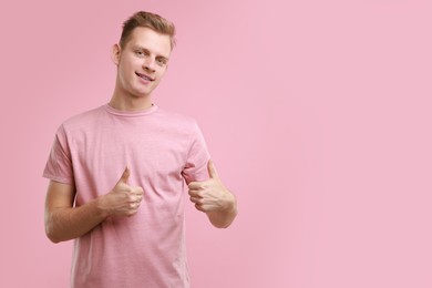 Photo of Happy man showing thumbs up on pink background, space for text. Like gesture