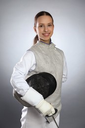 Photo of Smiling fencer with epee on gray background