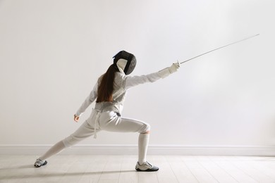 Photo of Fencer with epee practicing indoors. Combat sport