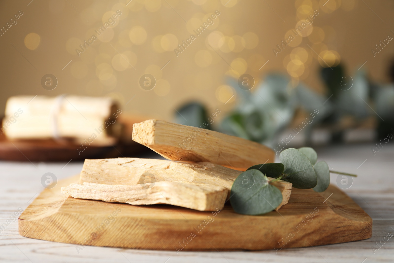 Photo of Palo santo sticks and eucalyptus branch on wooden table, closeup