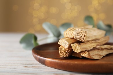 Photo of Palo santo sticks on wooden table, closeup. Space for text