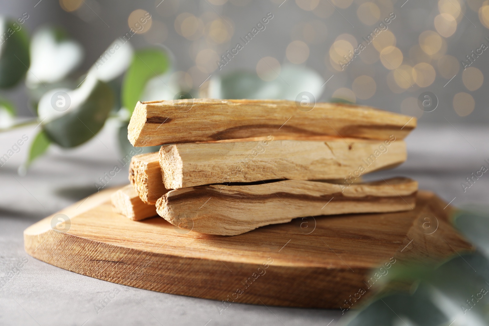 Photo of Palo santo sticks and eucalyptus leaves on grey table, closeup