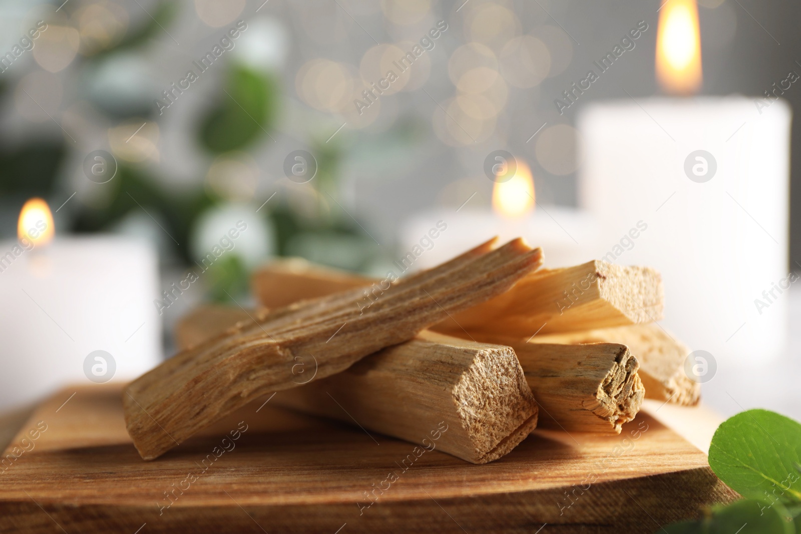 Photo of Palo santo sticks and burning candles on table, closeup