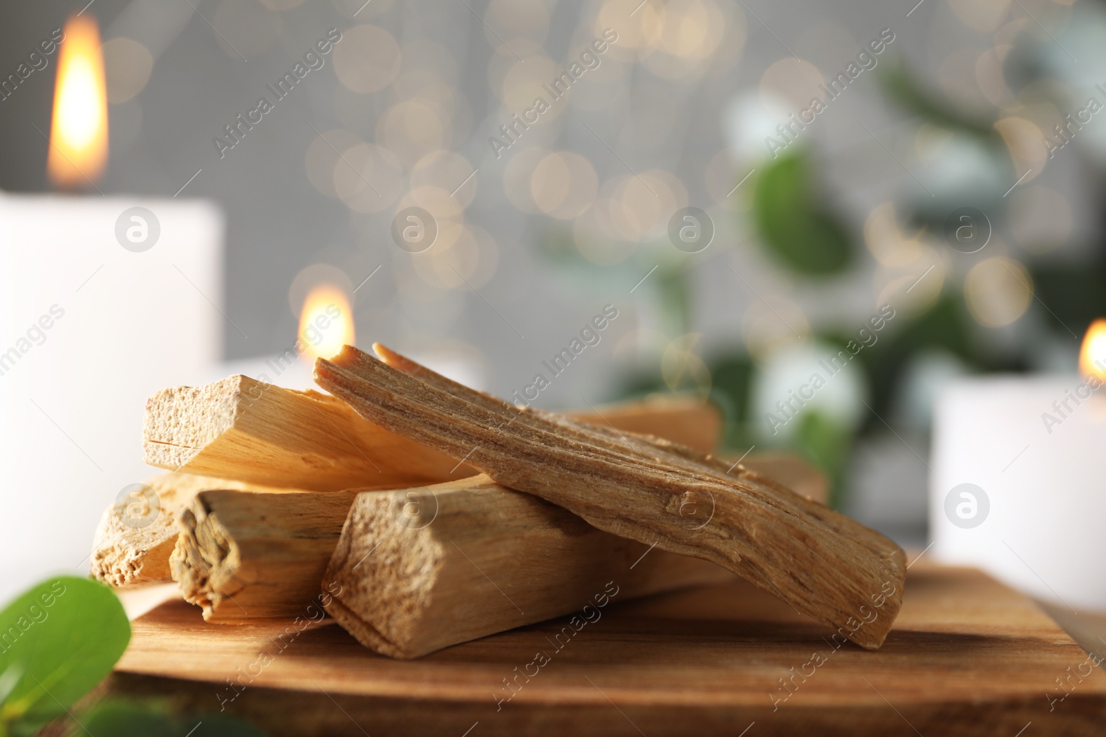 Photo of Palo santo sticks and burning candles on table, closeup