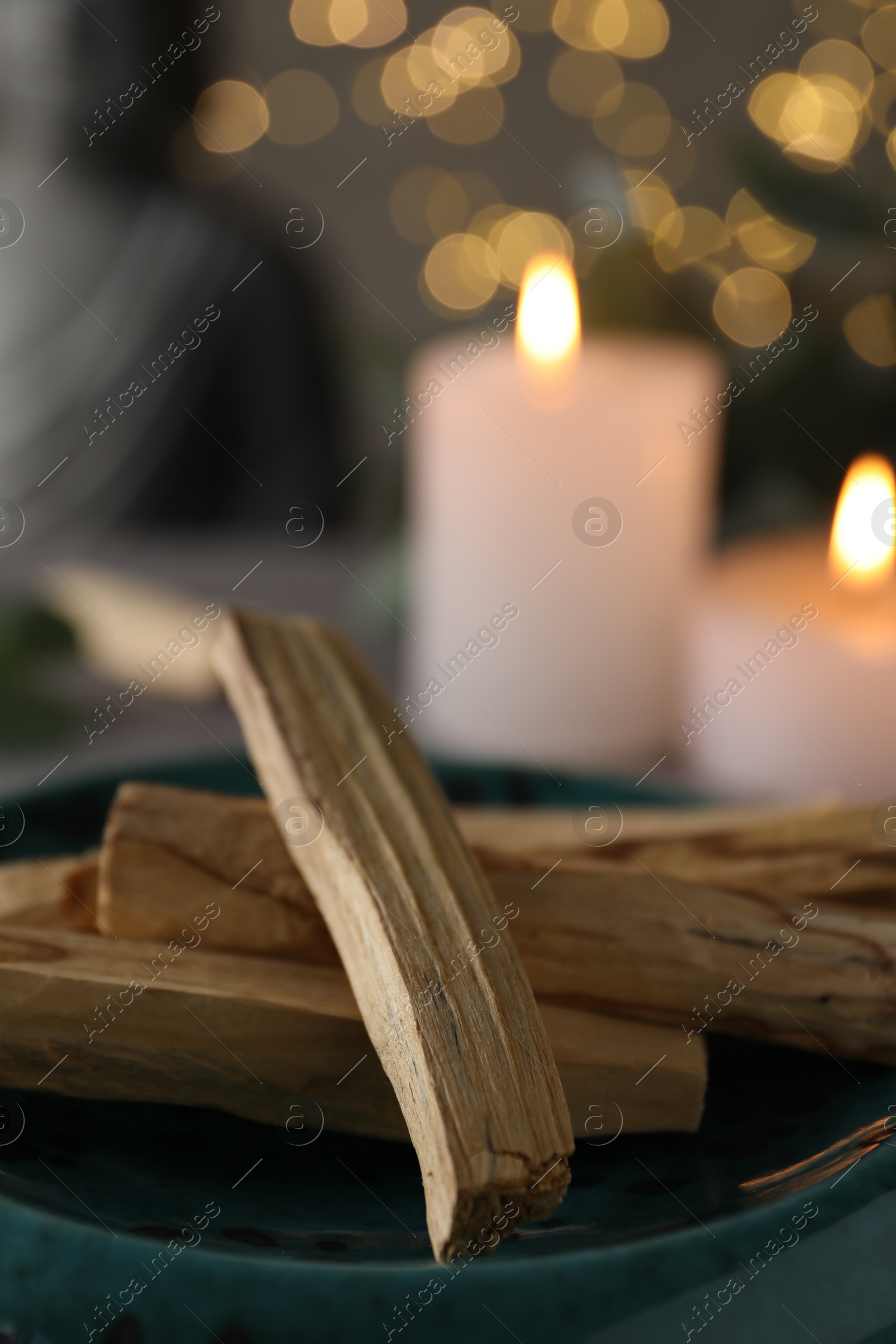 Photo of Palo santo sticks and burning candles on table, closeup