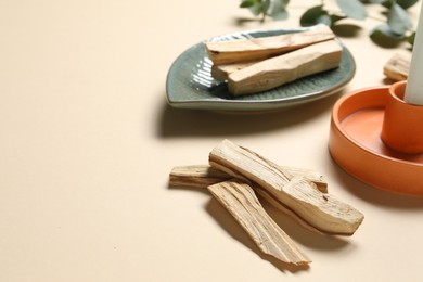 Photo of Palo santo sticks on beige background, closeup. Space for text