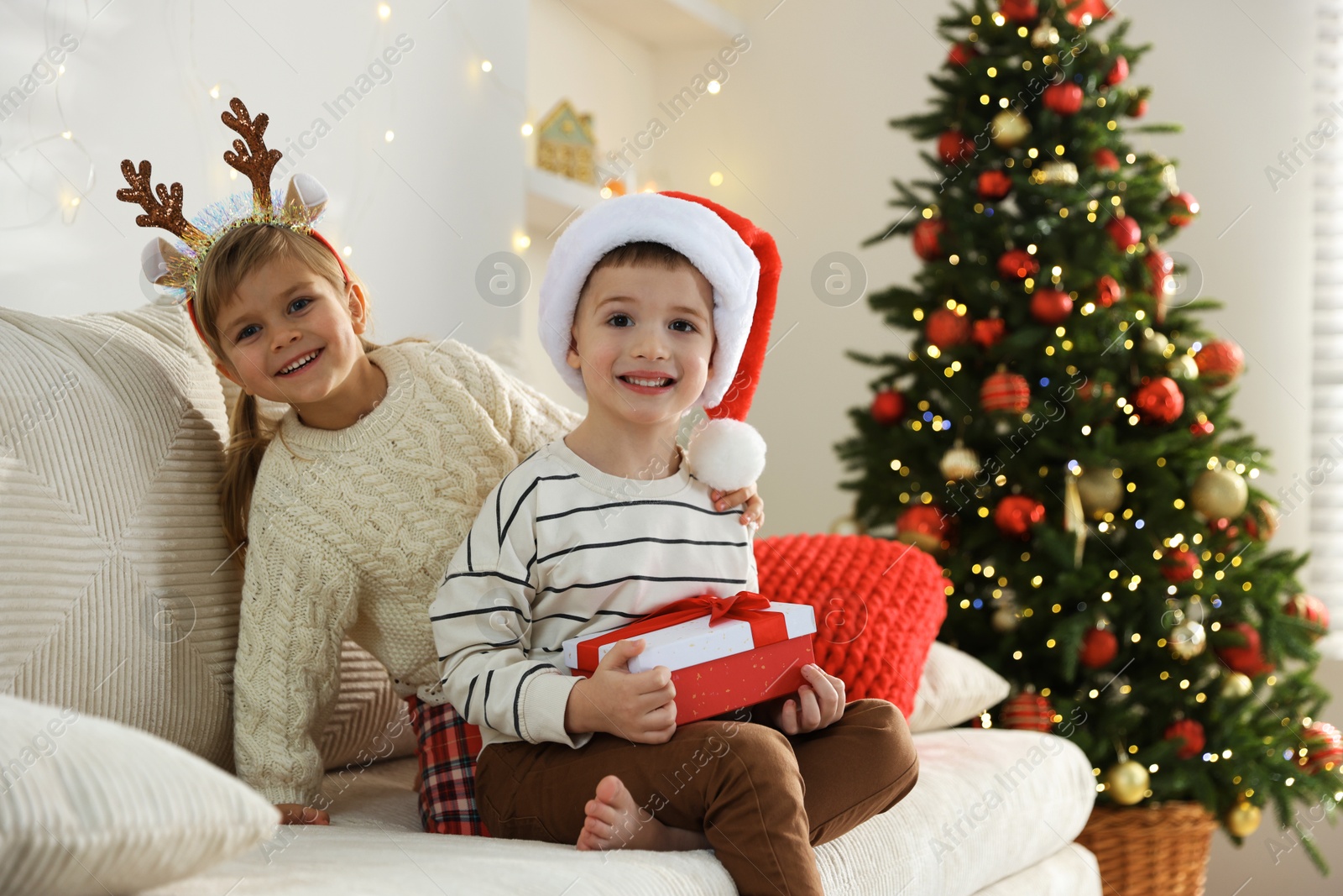 Photo of Happy children with Christmas gift on sofa at home