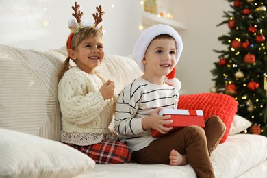 Happy children with Christmas gift on sofa at home