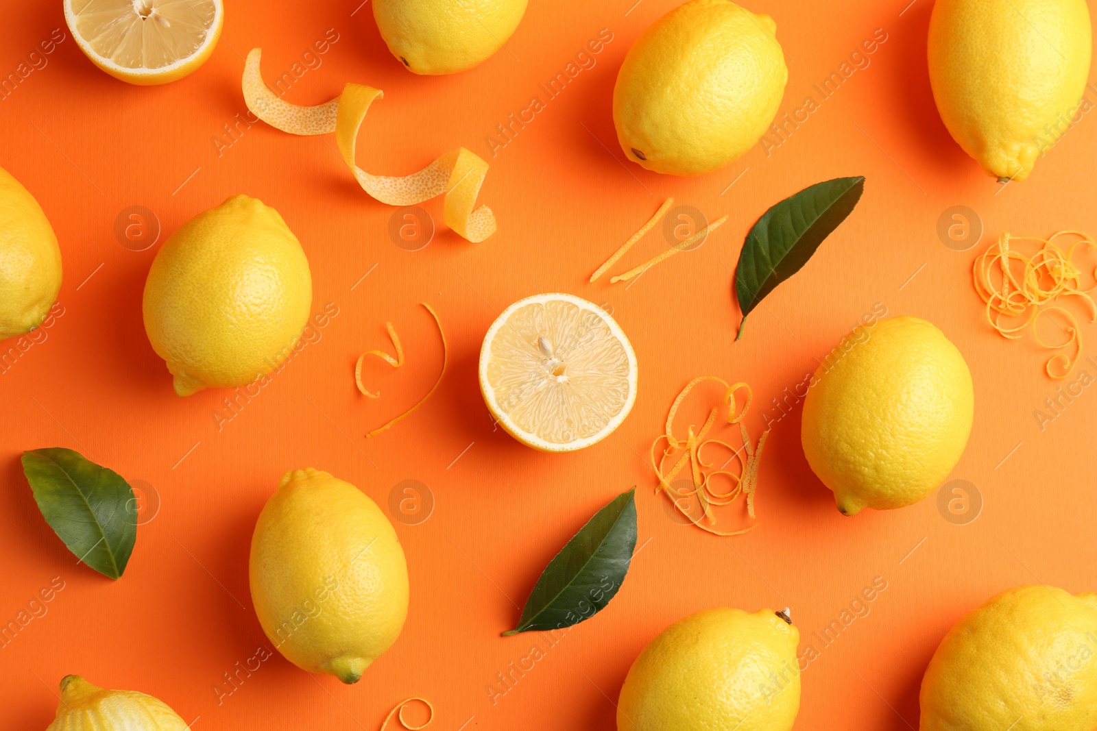 Photo of Lemon zest, fresh fruits and leaves on orange background, flat lay