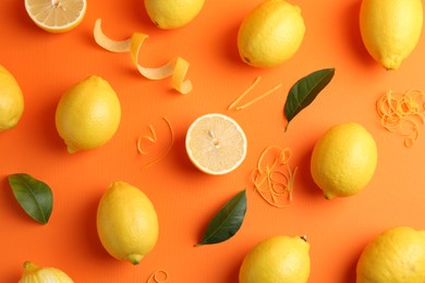 Photo of Lemon zest, fresh fruits and leaves on orange background, flat lay