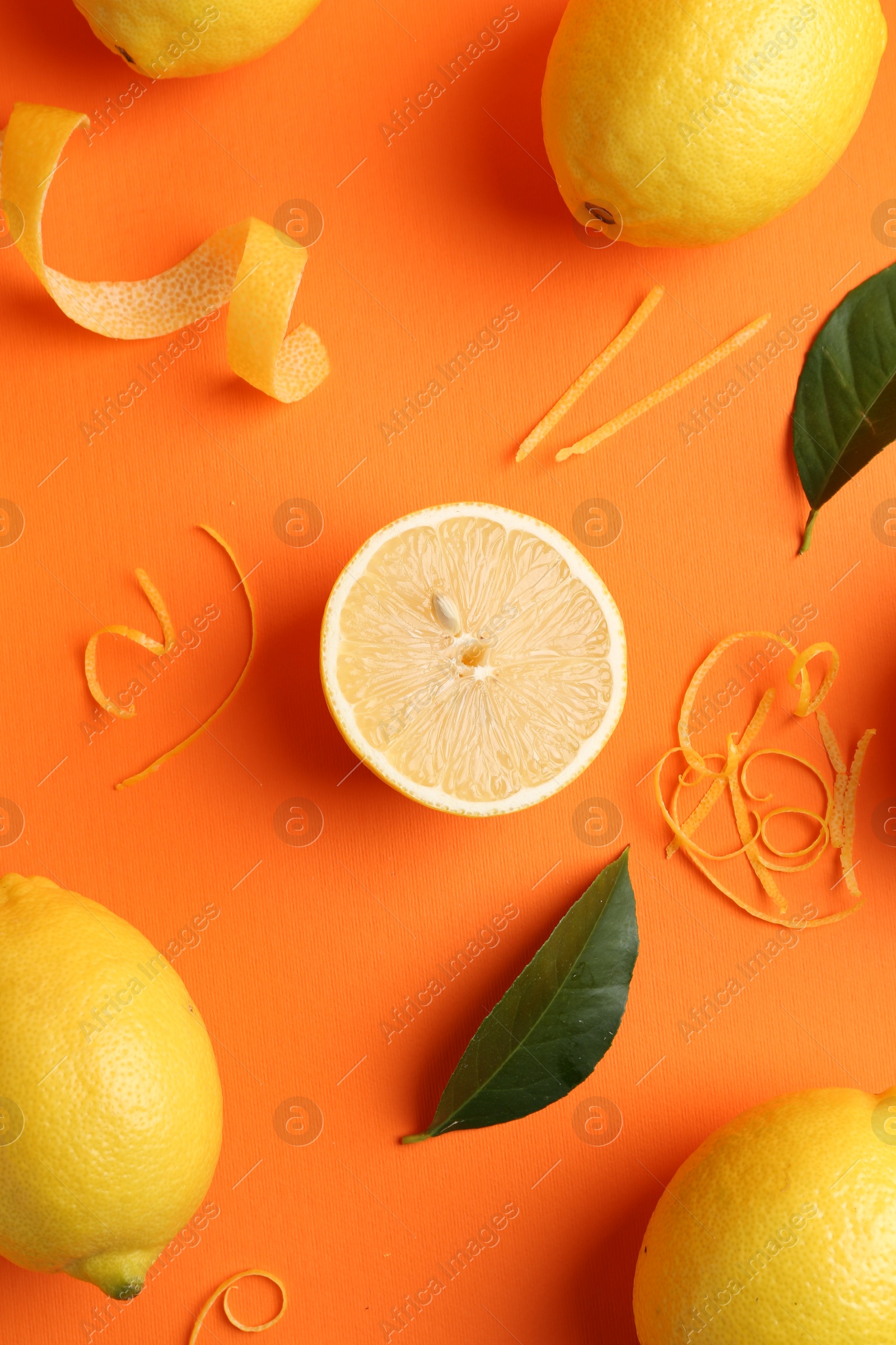 Photo of Lemon zest, fresh fruits and leaves on orange background, flat lay