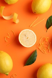 Photo of Lemon zest, fresh fruits and leaves on orange background, flat lay