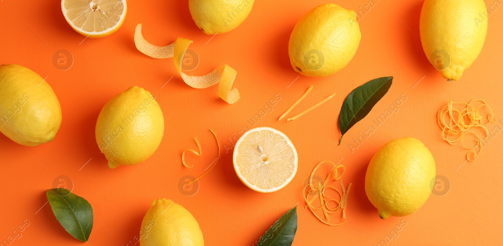 Photo of Lemon zest, fresh fruits and leaves on orange background, flat lay