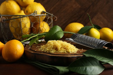 Photo of Lemon zest, grater and fresh fruits on wooden table