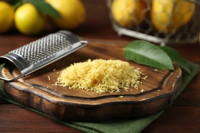 Photo of Lemon zest, grater and fresh fruits on wooden table, closeup