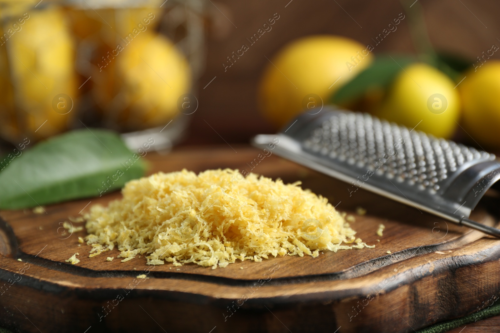 Photo of Lemon zest, grater and fresh fruits on wooden table, closeup