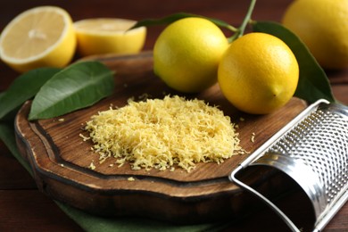 Photo of Lemon zest, grater and fresh fruits on wooden table, closeup