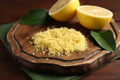 Photo of Lemon zest and fresh fruit pieces on wooden table, closeup