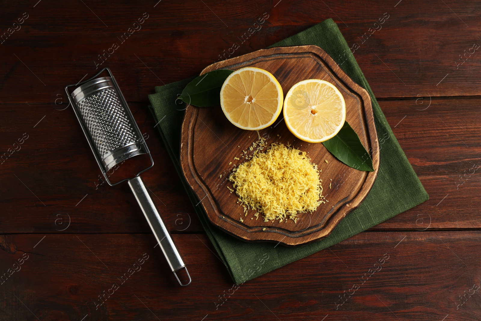 Photo of Lemon zest, grater and fresh fruit pieces on wooden table, top view