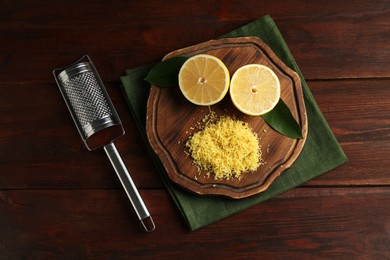 Photo of Lemon zest, grater and fresh fruit pieces on wooden table, top view