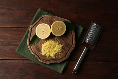 Photo of Lemon zest, grater and fresh fruit pieces on wooden table, top view