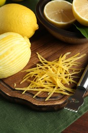 Photo of Lemon zest, zester tool and fresh fruits on wooden table, closeup