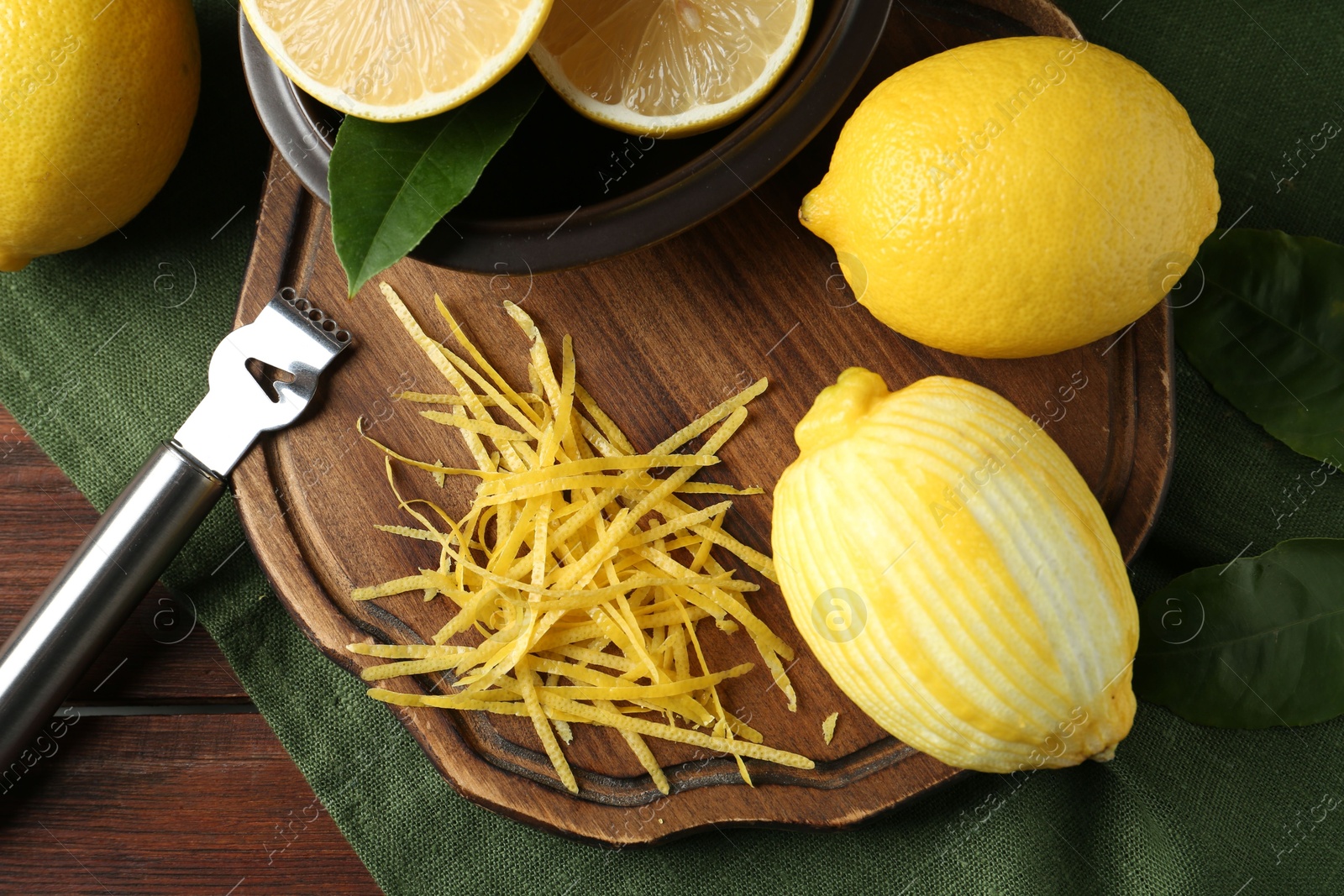 Photo of Lemon zest, zester tool and fresh fruits on wooden table, flat lay