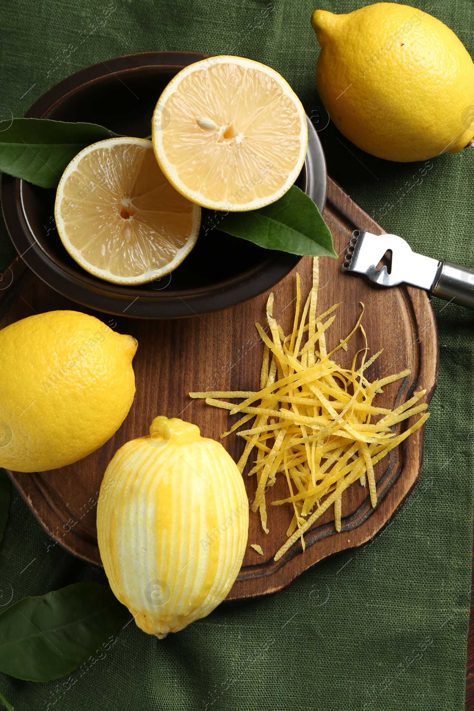 Photo of Lemon zest, zester tool and fresh fruits on table, flat lay