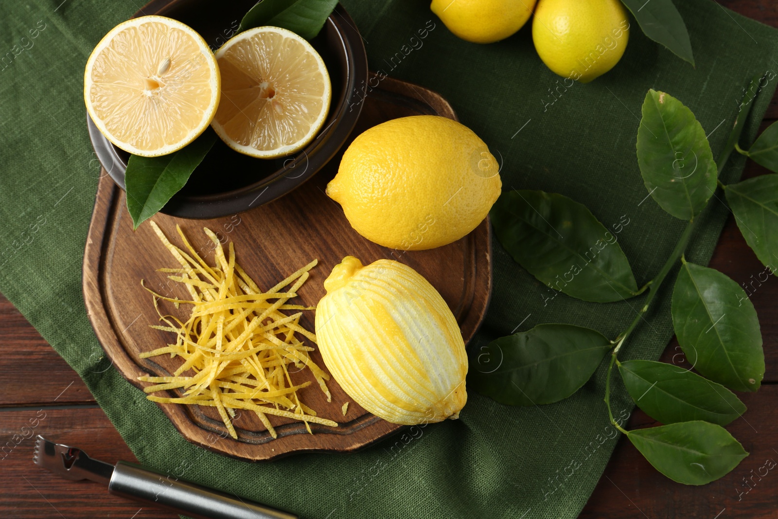 Photo of Lemon zest, zester tool and fresh fruits on wooden table, flat lay