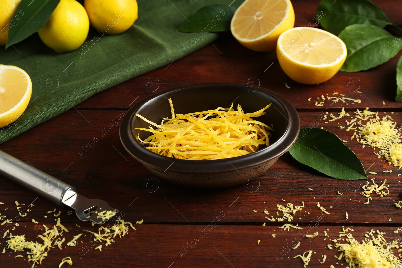 Photo of Lemon zest, zester tool and fresh fruits on wooden table, closeup