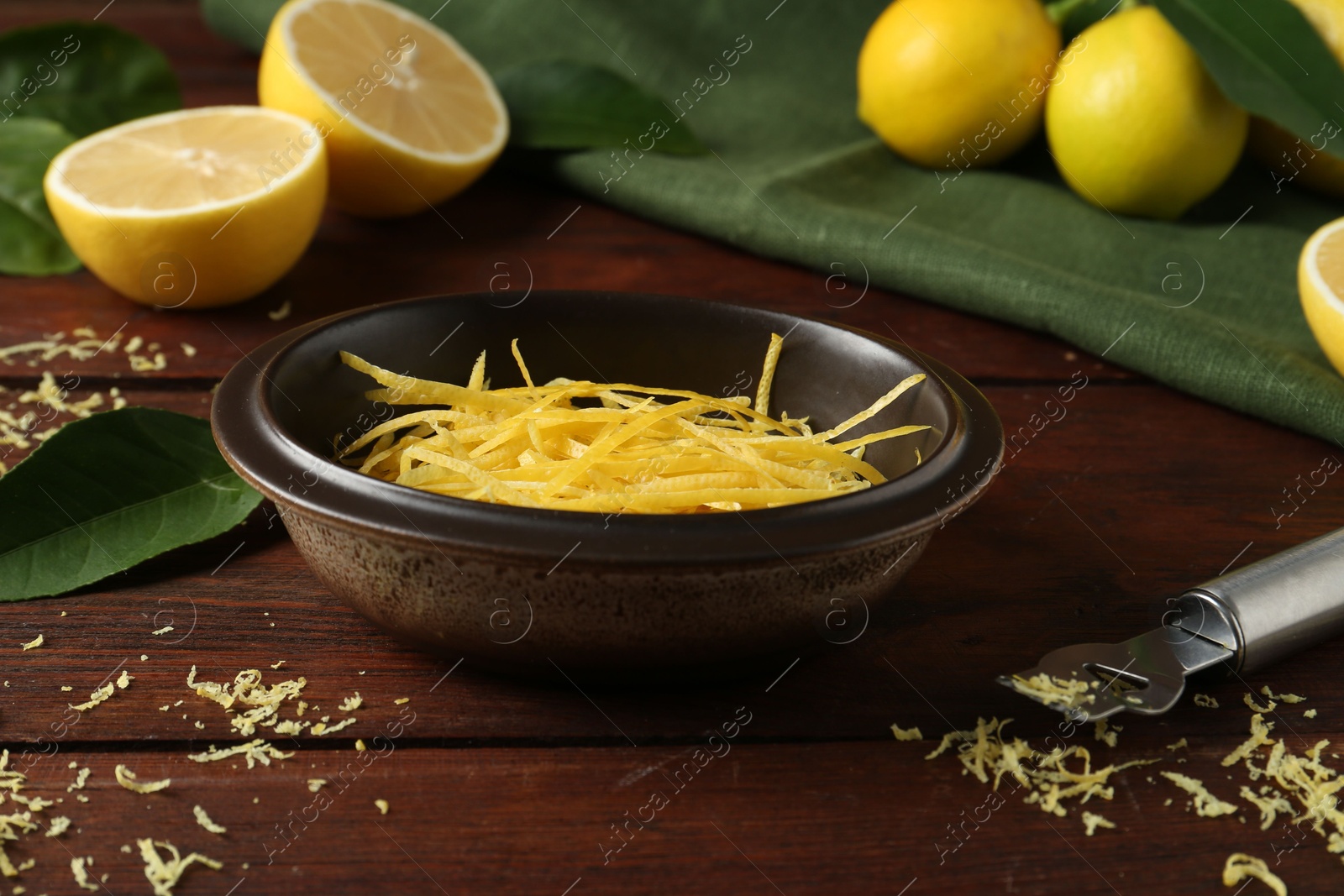 Photo of Lemon zest, zester tool and fresh fruits on wooden table, closeup