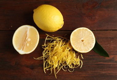 Photo of Lemon zest and fresh fruits on wooden table, flat lay