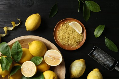 Photo of Lemon zest, grater and fresh fruits on black wooden table, flat lay