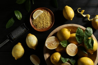 Photo of Lemon zest, grater and fresh fruits on black wooden table, flat lay