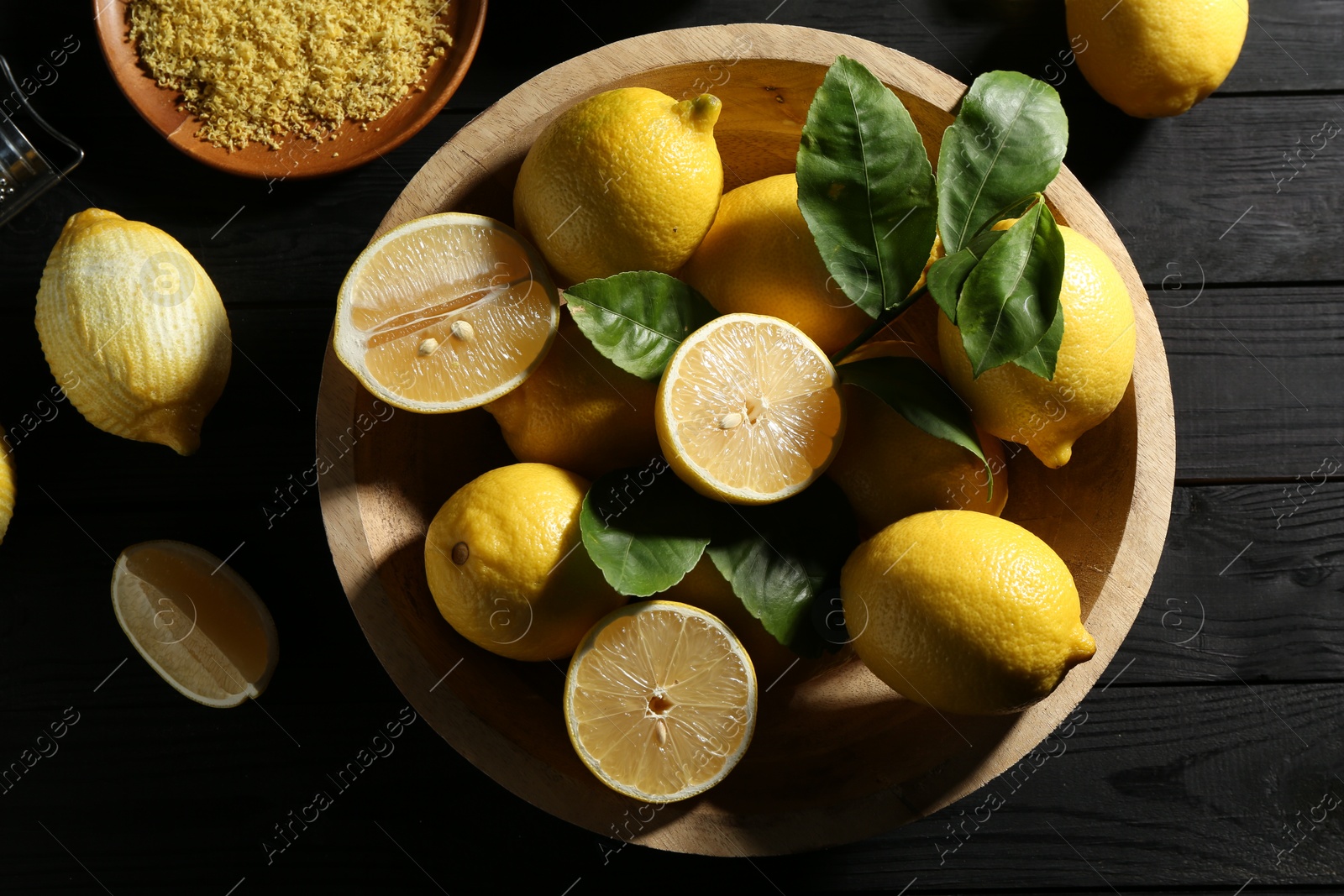 Photo of Lemon zest and fresh fruits on black wooden table, flat lay