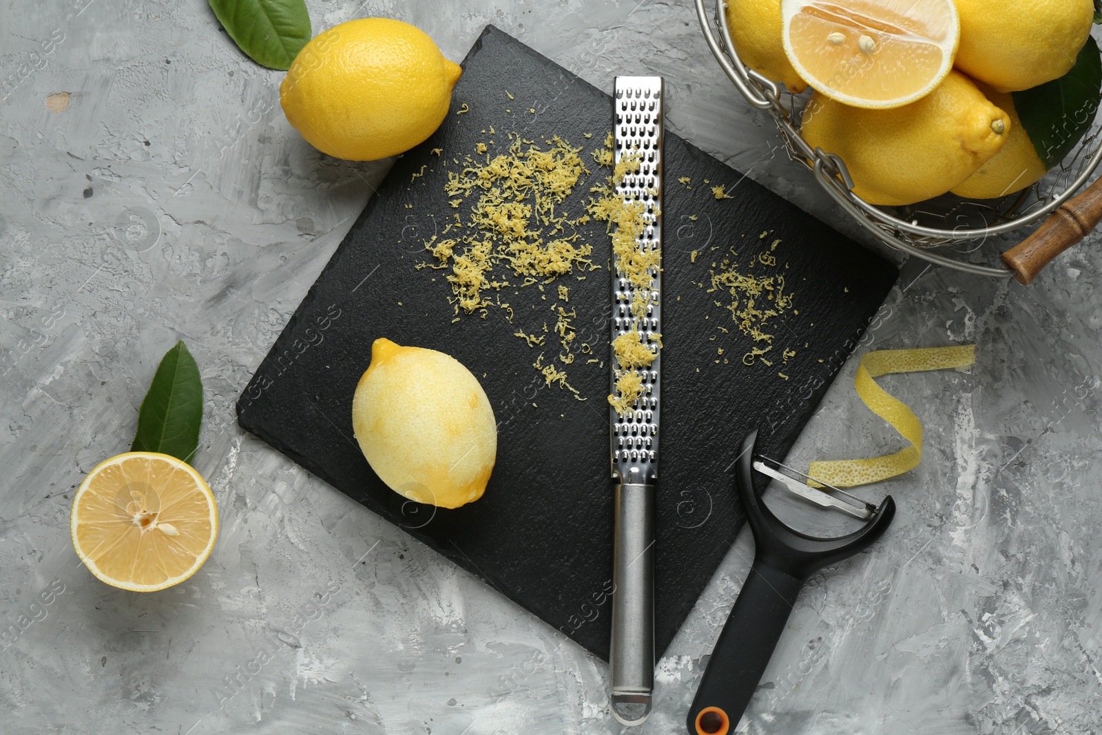 Photo of Lemon zest, tools and fresh fruits on grey textured table, flat lay