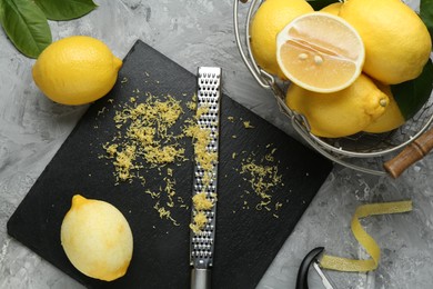 Photo of Lemon zest, tools and fresh fruits on grey textured table, flat lay