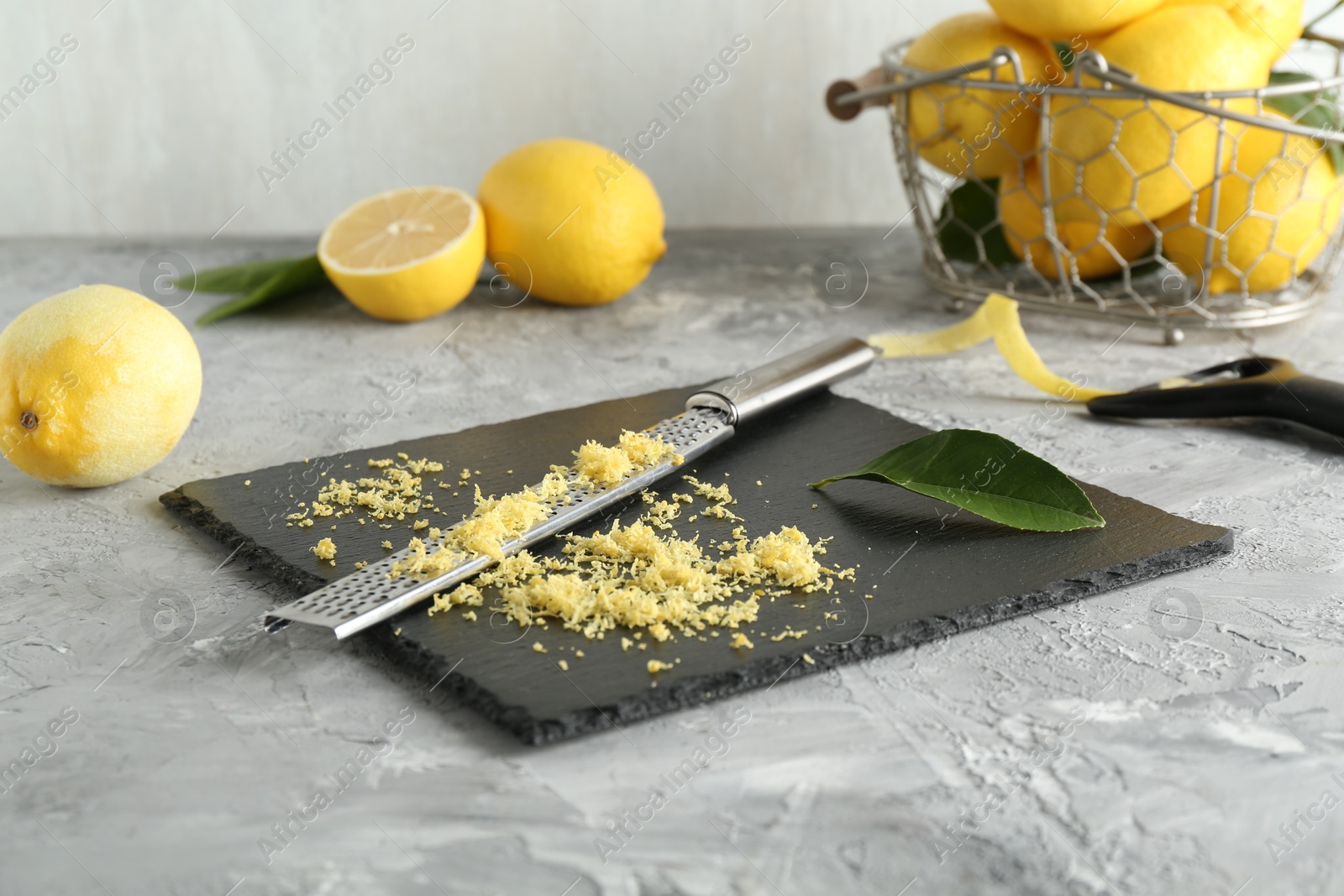 Photo of Lemon zest, tools and fresh fruits on grey textured table