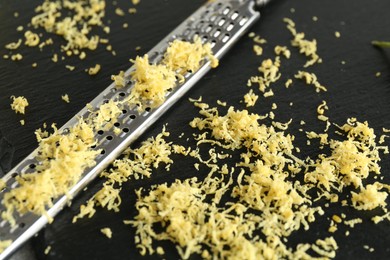 Photo of Fresh lemon zest and grater on slate board, closeup