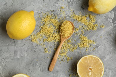 Photo of Lemon zest, fresh fruits and spoon on grey textured table, flat lay