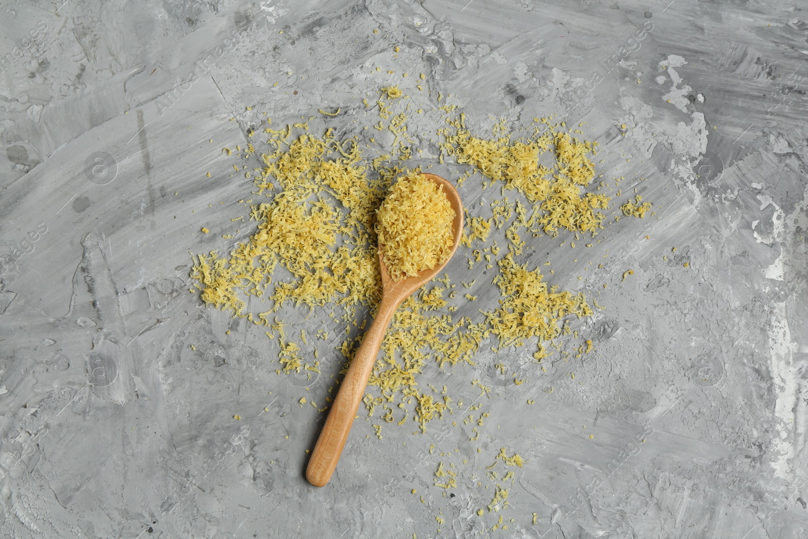 Photo of Lemon zest and spoon on grey textured table, top view