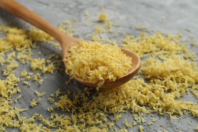 Photo of Lemon zest and spoon on grey textured table, closeup