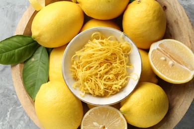 Photo of Lemon zest and fresh fruits in bowl on grey textured table, top view