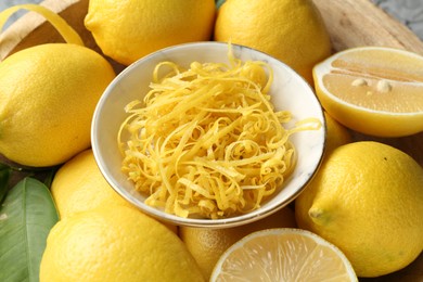 Photo of Lemon zest in bowl on fresh fruits, closeup